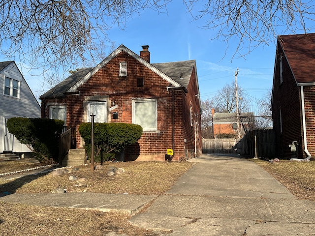 10026 Coyle St, Detroit, MI 48227 - view of front of property with fence, a chimney, brick siding, driveway, and a shingled roof