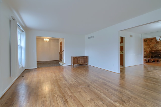 unfurnished living room with visible vents, a chandelier, and wood finished floors