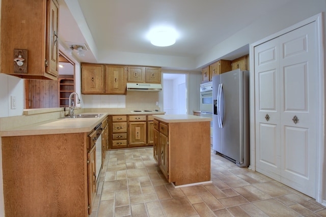 kitchen with light countertops, a sink, a center island, under cabinet range hood, and white appliances