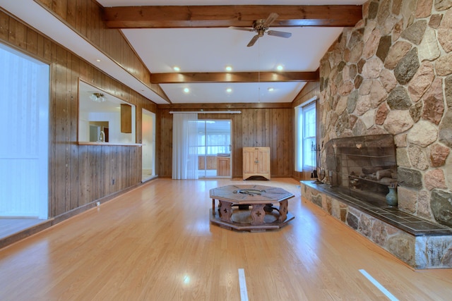 unfurnished living room with wood walls, plenty of natural light, a ceiling fan, and wood finished floors