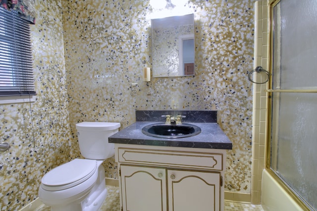 bathroom with toilet, vanity, and shower / bath combination with glass door