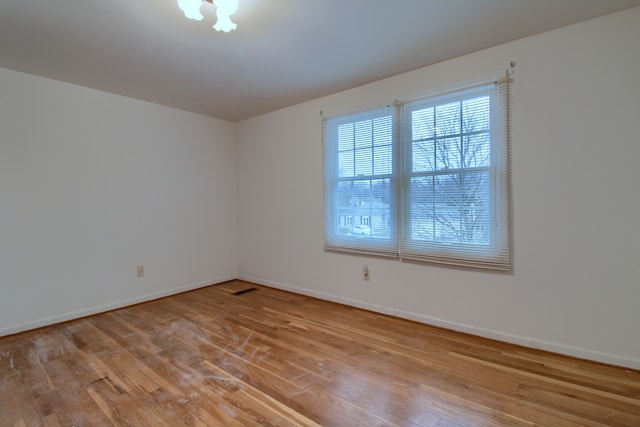 unfurnished room featuring baseboards, visible vents, and wood finished floors