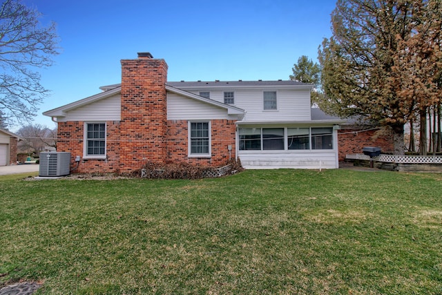 rear view of house featuring central air condition unit, a lawn, a chimney, and brick siding