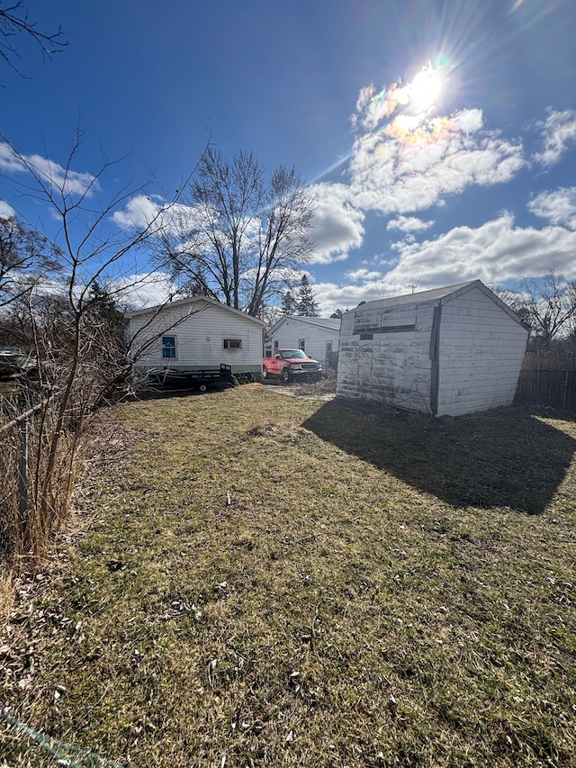 view of yard with an outdoor structure, fence, and a storage unit
