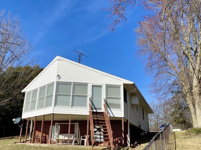 rear view of property featuring brick siding, fence, and stairs