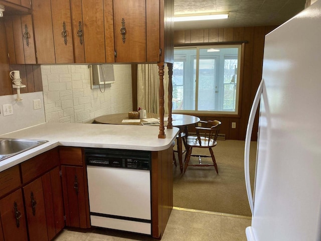 kitchen with a sink, decorative backsplash, brown cabinets, white appliances, and light countertops