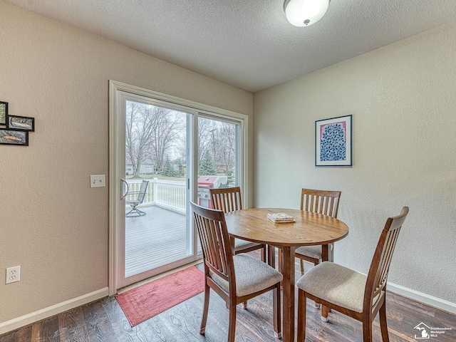 dining area featuring baseboards, a textured ceiling, a textured wall, and dark wood finished floors