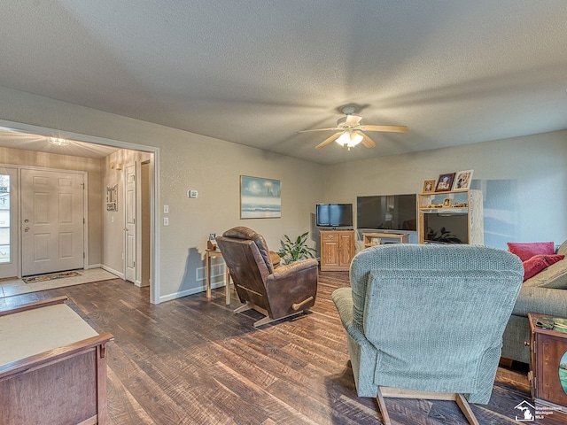 living area with a textured ceiling, baseboards, ceiling fan, and wood finished floors