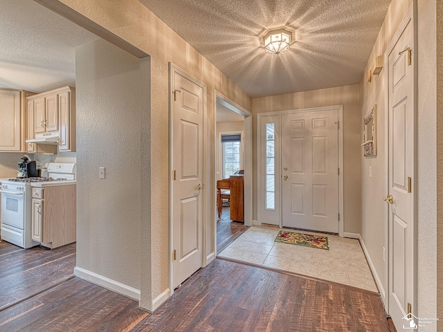 entryway with a textured wall, a textured ceiling, baseboards, and wood finished floors
