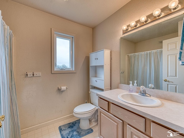 bathroom featuring a shower with curtain, vanity, toilet, a textured wall, and baseboards