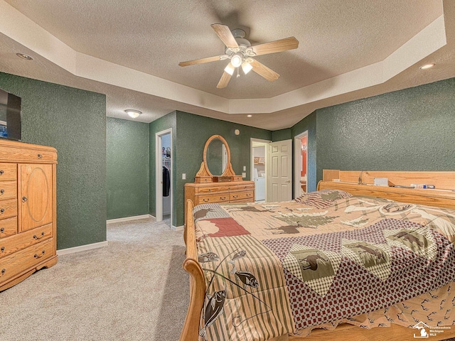 bedroom featuring carpet flooring, a textured wall, baseboards, a textured ceiling, and a raised ceiling