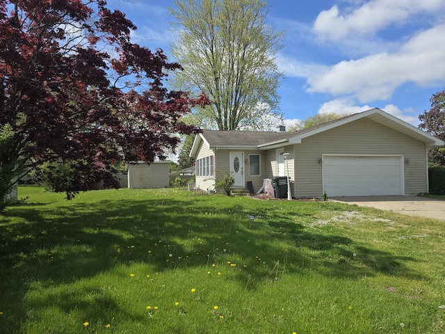 view of front of property with an attached garage, a storage shed, driveway, a front yard, and an outdoor structure