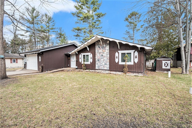view of front of property with a shed, concrete driveway, a front lawn, and an attached garage