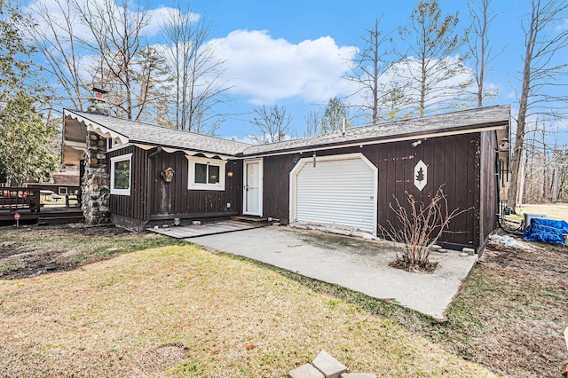 view of front of property featuring driveway, roof with shingles, a front lawn, a garage, and a deck