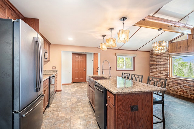 kitchen with a kitchen bar, a sink, stainless steel appliances, brick wall, and a notable chandelier