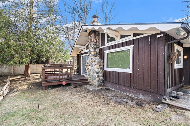 view of property exterior with fence, a deck, board and batten siding, and a chimney