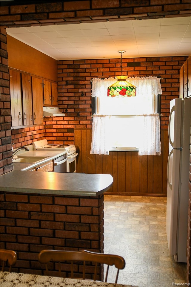 1521 Ferris Ave, Lincoln Park, MI 48146 - kitchen featuring white appliances, under cabinet range hood, brown cabinetry, a peninsula, and wood walls