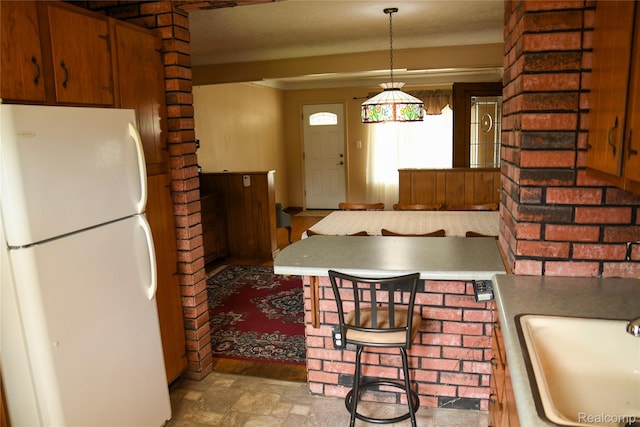 1521 Ferris Ave, Lincoln Park, MI 48146 - kitchen featuring freestanding refrigerator, a sink, stone finish floors, decorative light fixtures, and brown cabinets
