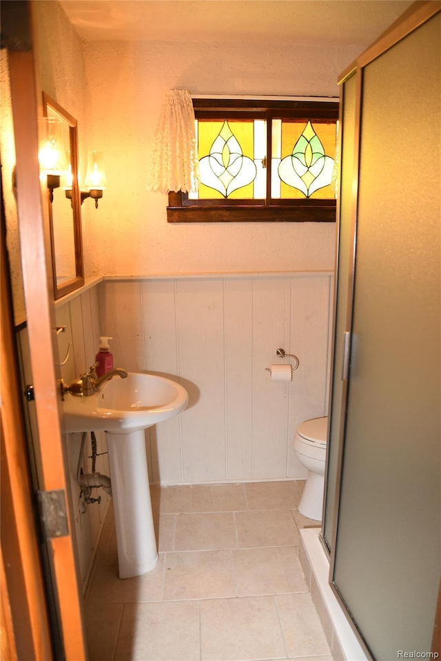 1521 Ferris Ave, Lincoln Park, MI 48146 - bathroom with a stall shower, toilet, tile patterned floors, a wainscoted wall, and a sink