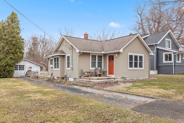 view of front facade with a front lawn, a chimney, fence, and roof with shingles