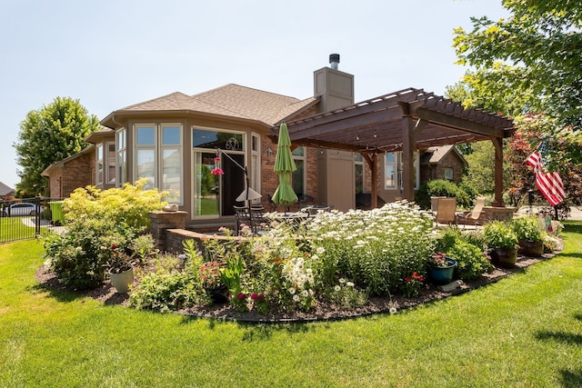 back of property with a pergola, a chimney, a lawn, brick siding, and fence