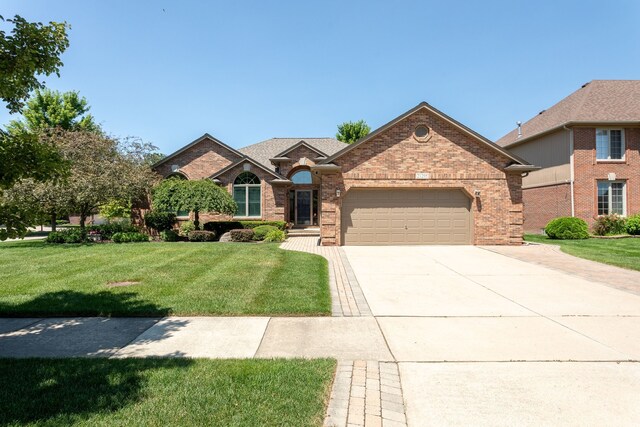 view of front of house featuring a front yard, a garage, concrete driveway, and brick siding