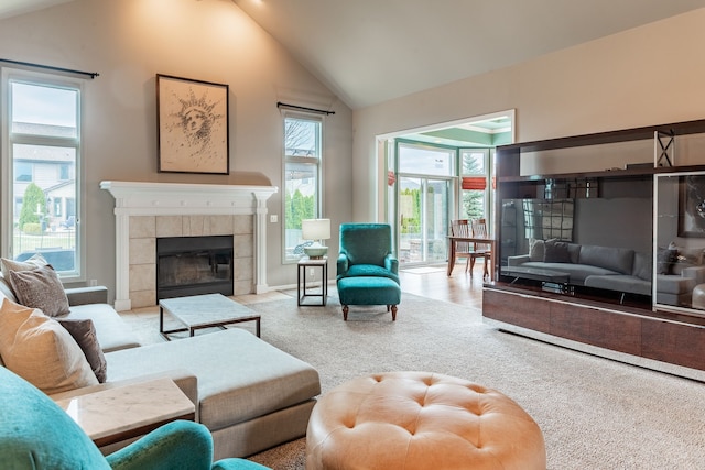 carpeted living room with a tiled fireplace and high vaulted ceiling