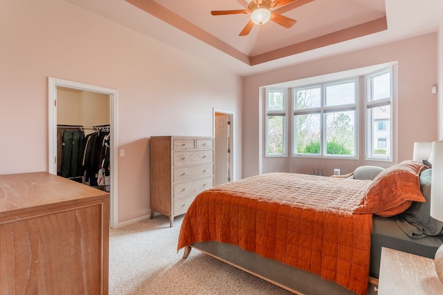 bedroom featuring a closet, a spacious closet, baseboards, and light carpet