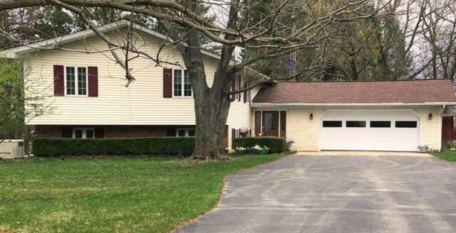 tri-level home featuring a front lawn, driveway, and a garage
