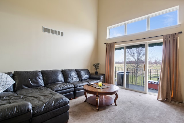 living room featuring carpet flooring, a high ceiling, and visible vents