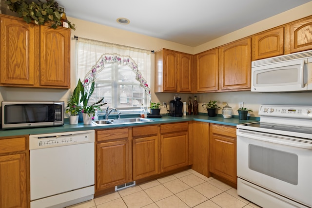 kitchen with white appliances, light tile patterned floors, a sink, visible vents, and brown cabinets