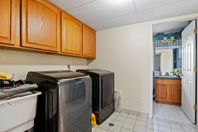 clothes washing area featuring baseboards, separate washer and dryer, a sink, light tile patterned flooring, and cabinet space