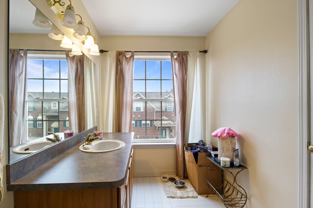 bathroom with baseboards, a chandelier, vanity, and plenty of natural light