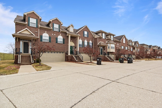 townhome / multi-family property featuring driveway, roof with shingles, brick siding, a residential view, and a garage