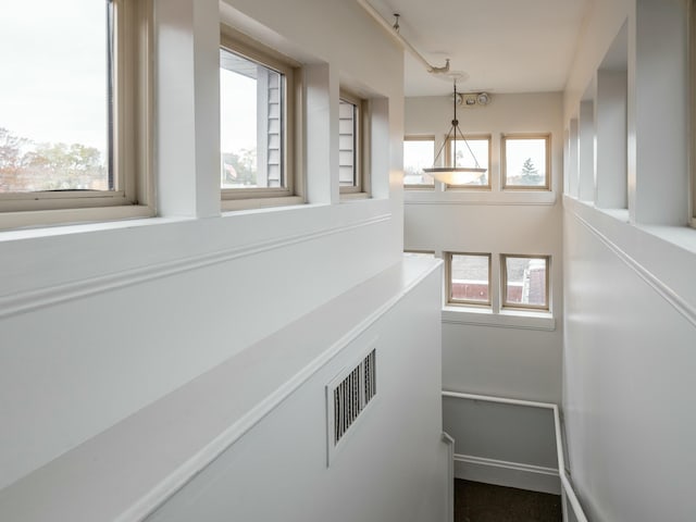 hall featuring baseboards and visible vents