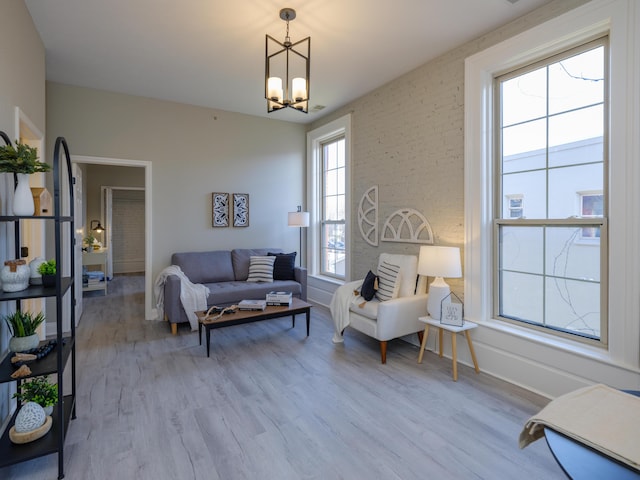 living area featuring a notable chandelier, baseboards, and light wood finished floors