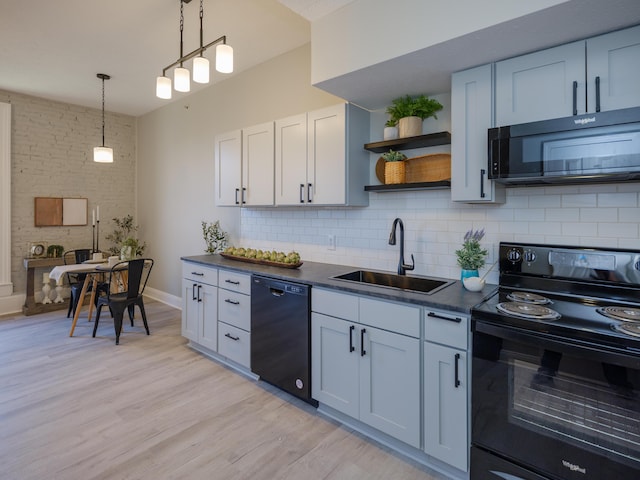 kitchen featuring open shelves, light wood-type flooring, a sink, dark countertops, and black appliances