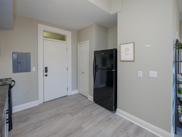 kitchen with electric panel, baseboards, light wood-style floors, and freestanding refrigerator