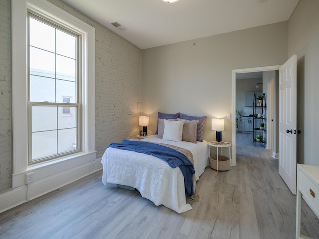 bedroom featuring baseboards, light wood-type flooring, and visible vents