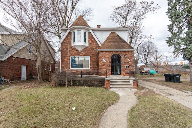16917 Griggs St, Detroit, MI 48221 - tudor home featuring a front lawn, a chimney, brick siding, and roof with shingles