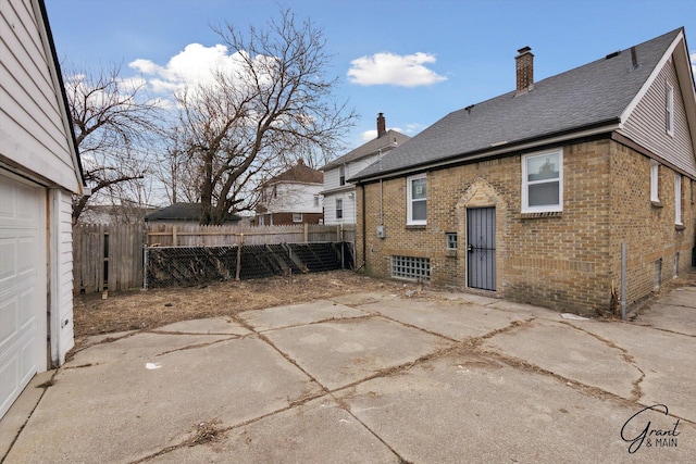 10088 Britain St, Detroit, MI 48224 - rear view of house with fence, a chimney, a patio, and brick siding