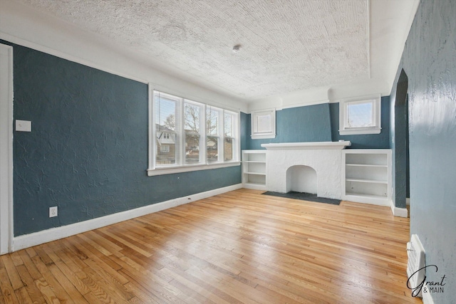 10088 Britain St, Detroit, MI 48224 - unfurnished living room featuring baseboards, a textured ceiling, light wood-style flooring, and a textured wall