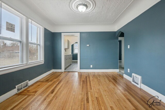 10088 Britain St, Detroit, MI 48224 - empty room featuring arched walkways, baseboards, light wood-style floors, and visible vents