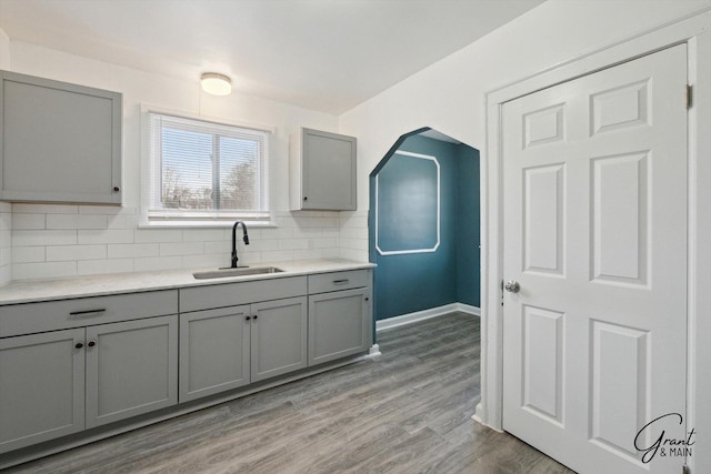 10088 Britain St, Detroit, MI 48224 - kitchen with light countertops, a sink, light wood finished floors, tasteful backsplash, and gray cabinetry