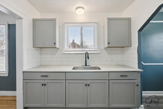 10088 Britain St, Detroit, MI 48224 - kitchen with backsplash, a sink, baseboards, and gray cabinetry