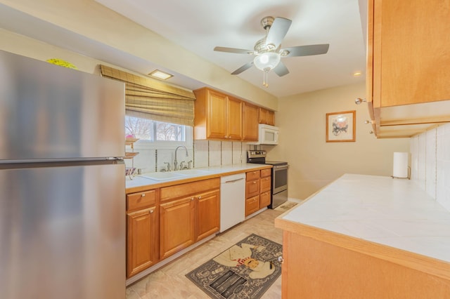3803 Miller Rd, Kalamazoo, MI 49001 - kitchen featuring stainless steel appliances, a sink, backsplash, ceiling fan, and tile counters