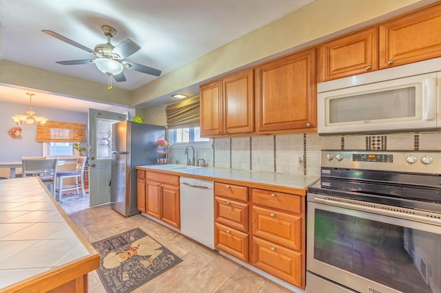 3803 Miller Rd, Kalamazoo, MI 49001 - kitchen with stainless steel appliances, tile counters, a sink, tasteful backsplash, and a chandelier