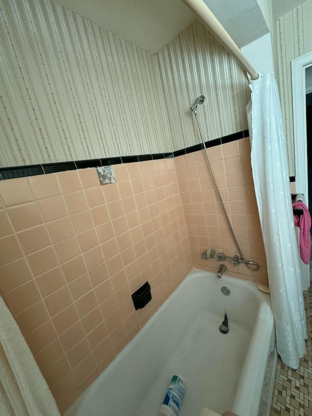 full bathroom with wallpapered walls, shower / bath combo with shower curtain, and a wainscoted wall