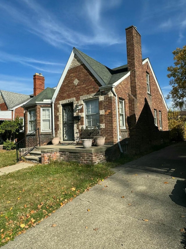view of front of house with a front lawn, a chimney, and brick siding