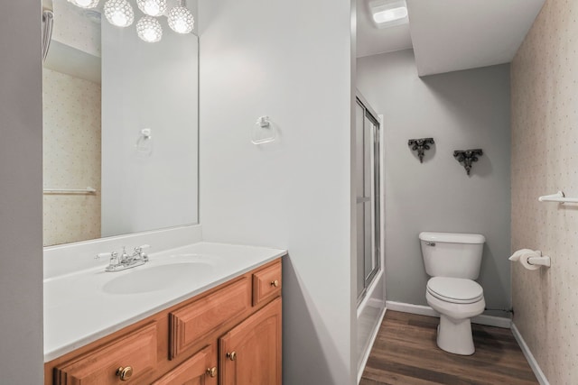 bathroom featuring vanity, toilet, baseboards, wallpapered walls, and wood finished floors